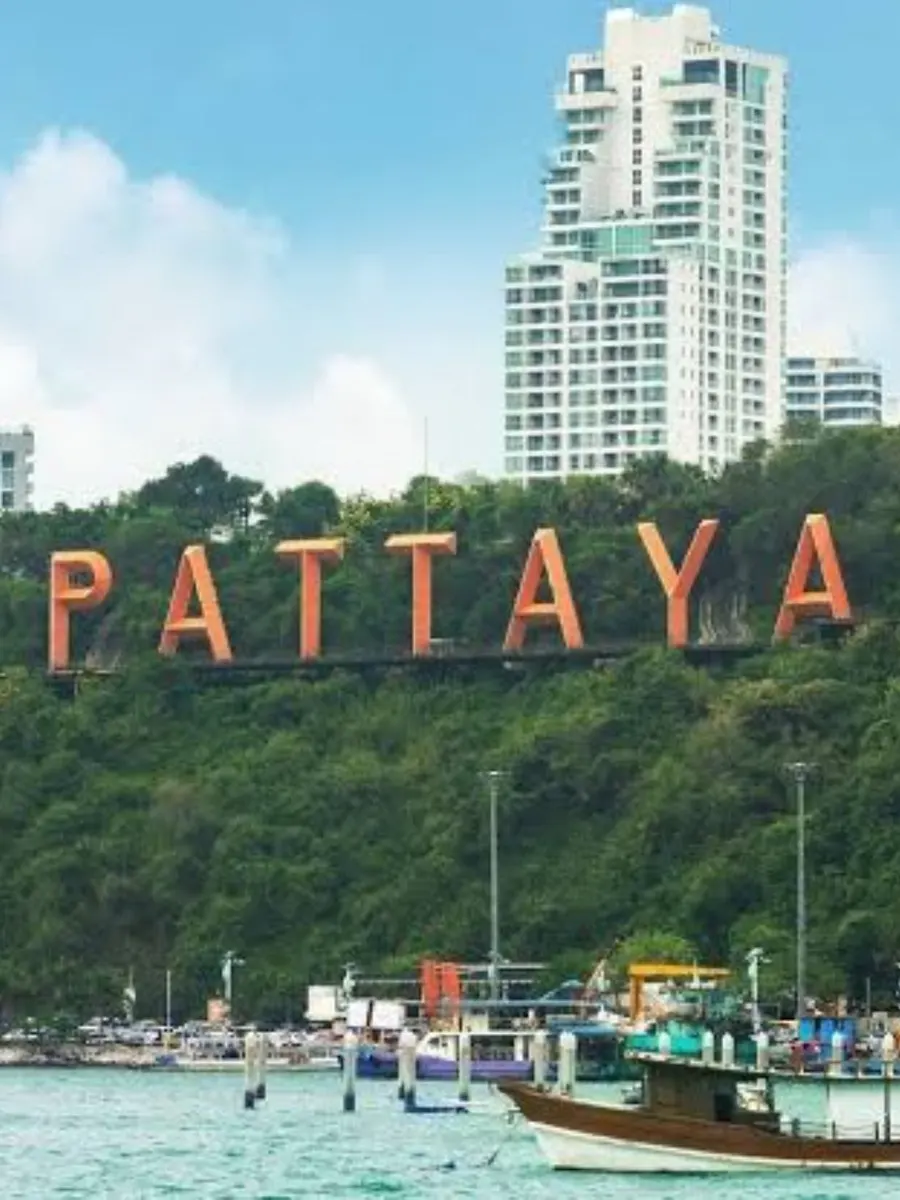 The giant PATTAYA letters on the green hillside above Pattaya Bay, with a wooden boat in the foreground
