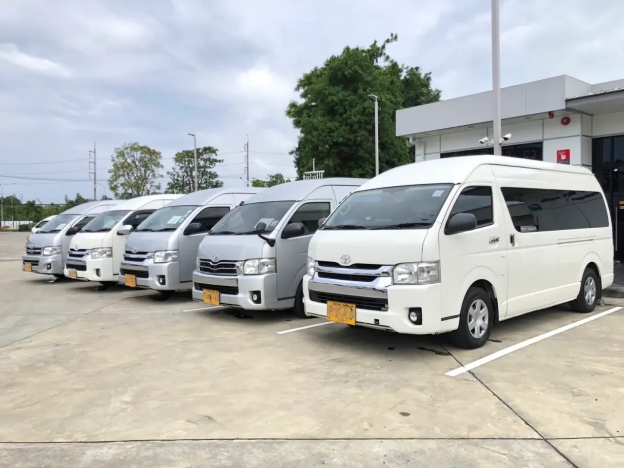 Une rangée de minibus blancs garés au dépôt, prêts pour des prises en charge privées à l’aéroport