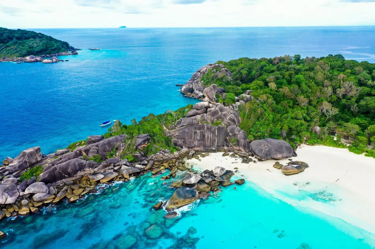 Vue aérienne d’un promontoire de blocs de granit, d’une plage de sable blanc et d’eaux turquoise peu profondes dans la mer d’Andaman