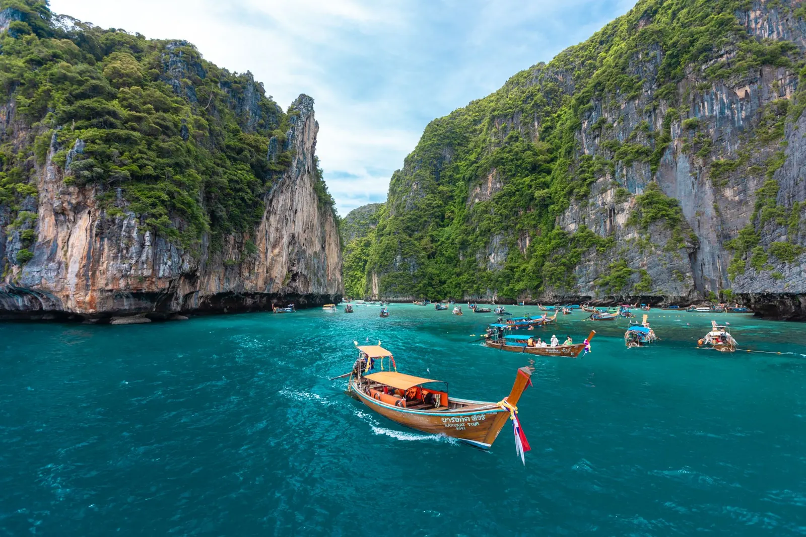 เรือหางยาวแล่นผ่านอ่าวปิเละระหว่างหน้าผาหินปูน
